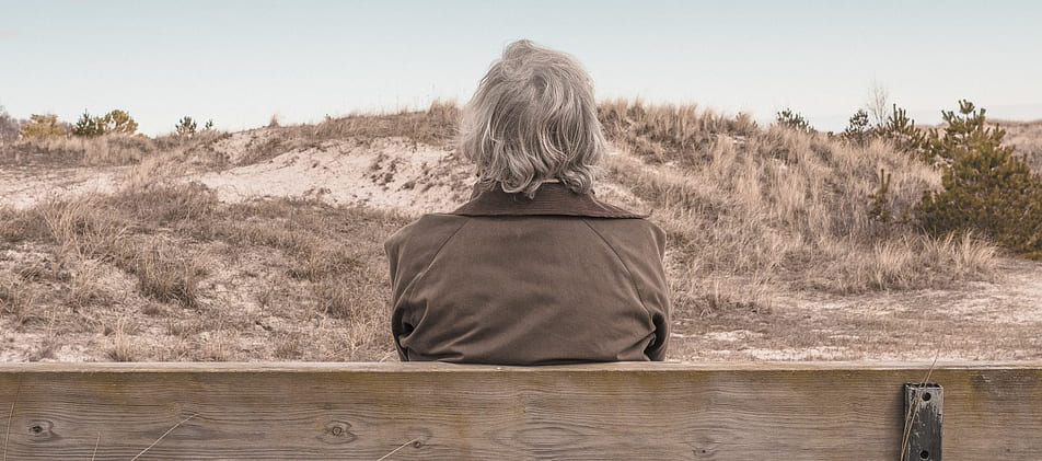 Ältere Dame genießt Ausblick in Dünenlandschaft - ganz entspannt nach Schuldenbereinigung Privatinsolvenz Flensburg