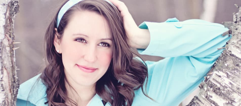 Junge Frau lehnt an Baumstamm und denkt lächelnd an schuldenfreie Zukunft dank schneller Hilfe durch Berater bei Privatinsolvenz Ludwigsburg